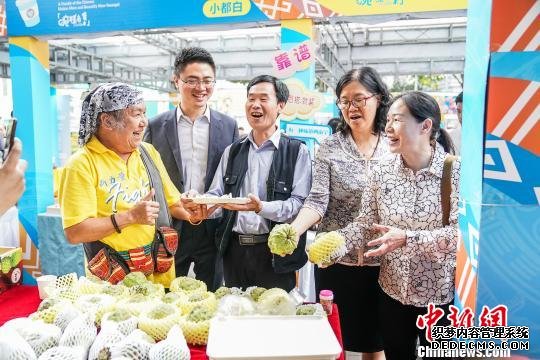 台湾歌手北原山猫吴廷宏（左一）和广西南宁市台协会长周代祥（左二）品尝台湾产的释迦果。　陈冠言 摄