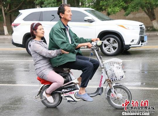 夫妻俩骑电动车上下班。　胡浩浩 摄