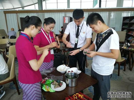 南航地服工作人员和候机旅客一起包粽子。尹丽腊 摄