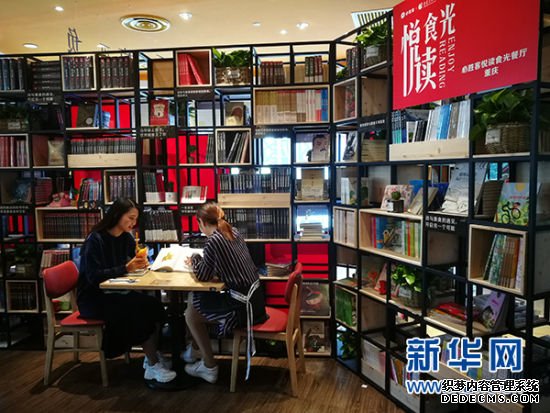 图为两位市民在餐厅内边吃美食边翻阅图书。新华网发(重庆出版集团供图)