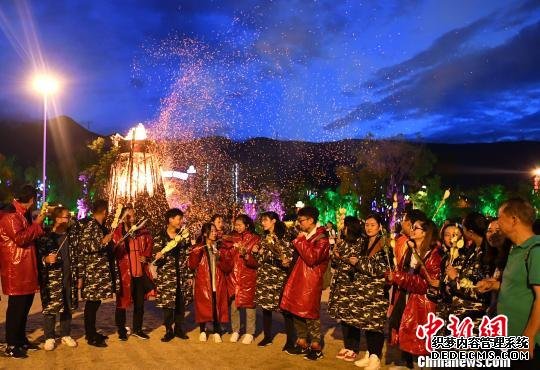 游客在丽江千古情景区身穿棉衣，围着篝火吃烧烤。丽江千古情景区供图