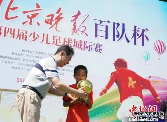 第四届北京晚报百队杯少儿足球城际赛在国家奥林匹克体育中心举行，足球名宿金志扬给获金球奖的小球员颁奖。主办方