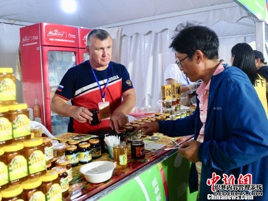 俄罗斯展商正在向市民介绍俄罗斯地产蜂蜜 刘栋 摄