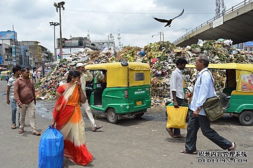 资料图片：2019年7月28日，在印度班加罗尔，人们从堆积成山的垃圾旁走过。（新华社）