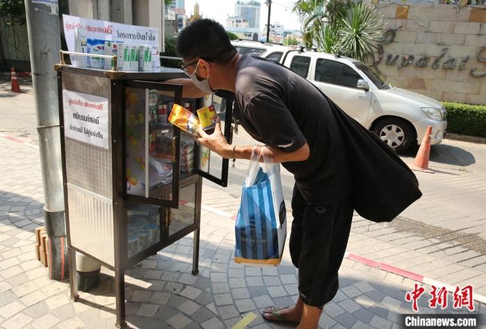 5月14日，一位市民在泰国曼谷一住宅小区路口的“共享食物柜”拿取物品。/p中新社记者 王国安 摄